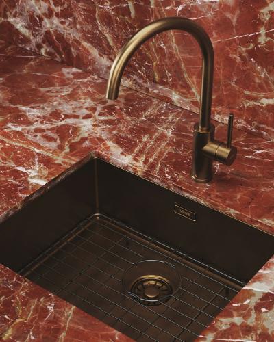 Exclusieve bronzen kraan en spoelbak met bodemrooster in rood marmeren keuken