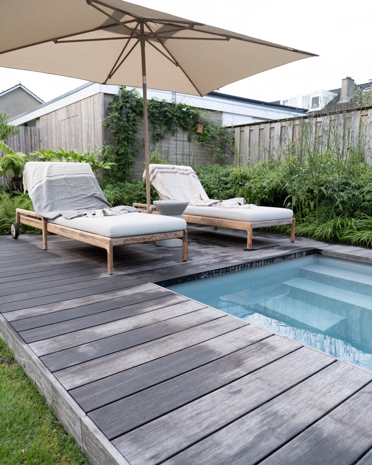 tuin met zwembad en loungestoelen