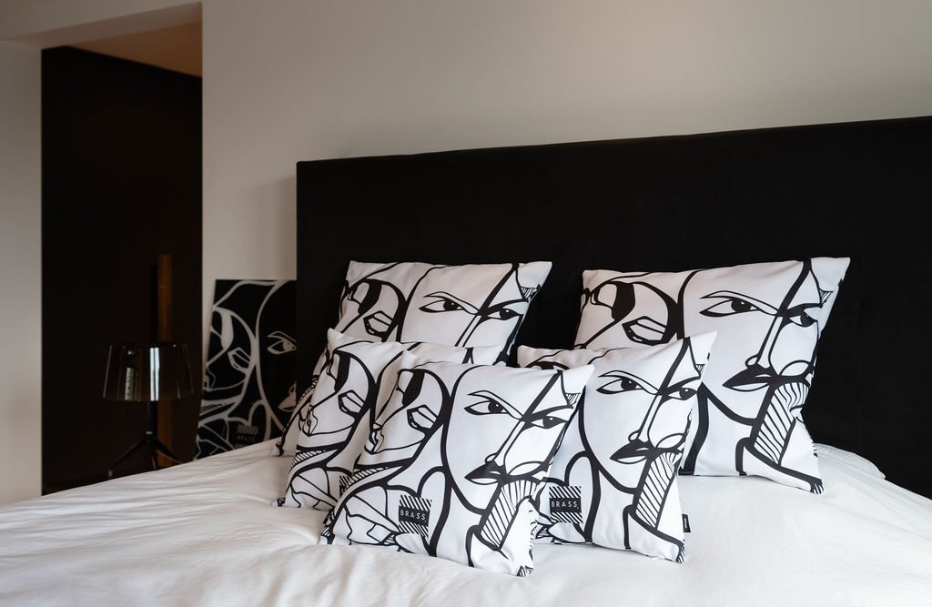 bed met sfeervolle kussens met kunst
